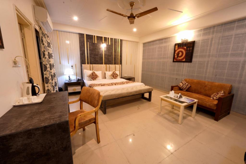 新德里Family Hotel Near IGI Airport的一间卧室配有一张床、一张沙发和一张桌子