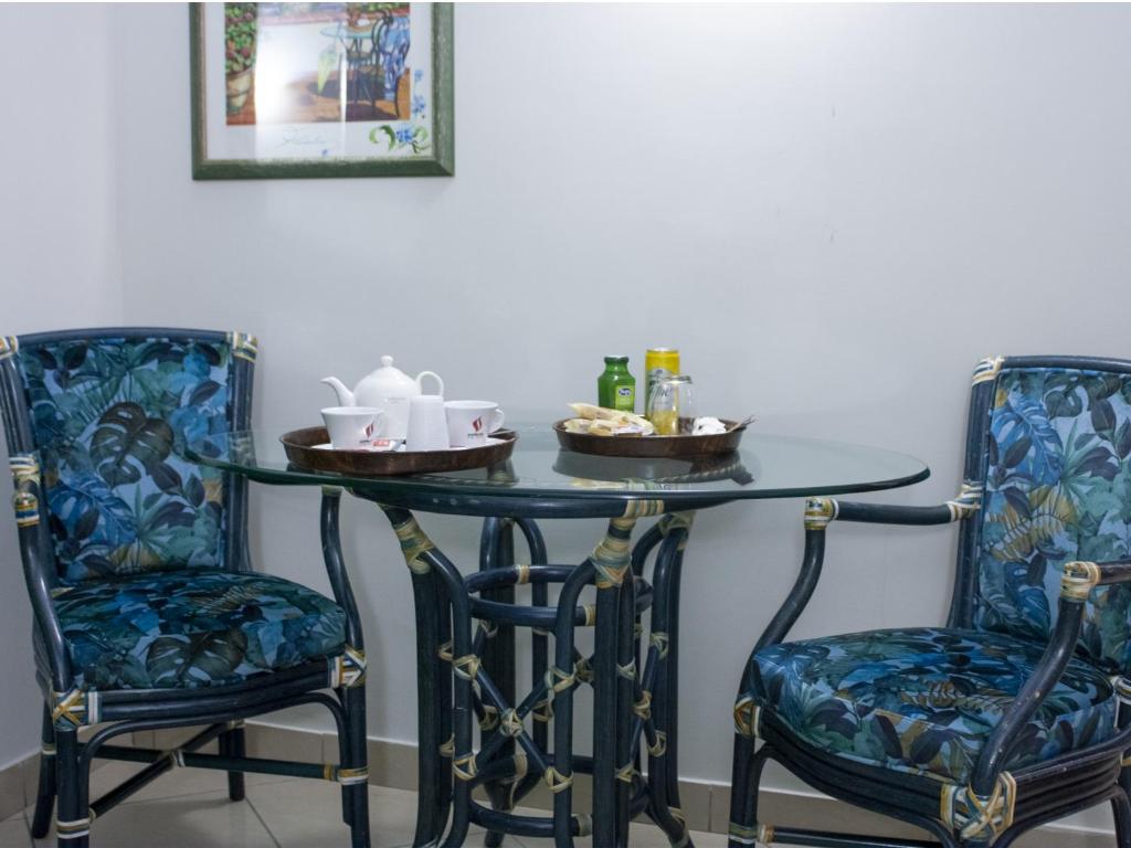 那不勒斯Hotel Serena的一张桌子、两把椅子和一张桌子,并备有饮料