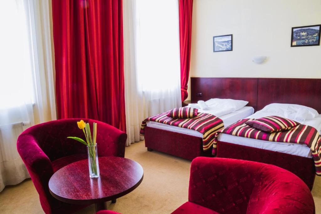 卡罗维发利Hotel Adria的酒店客房带两张床和一张桌子以及椅子。