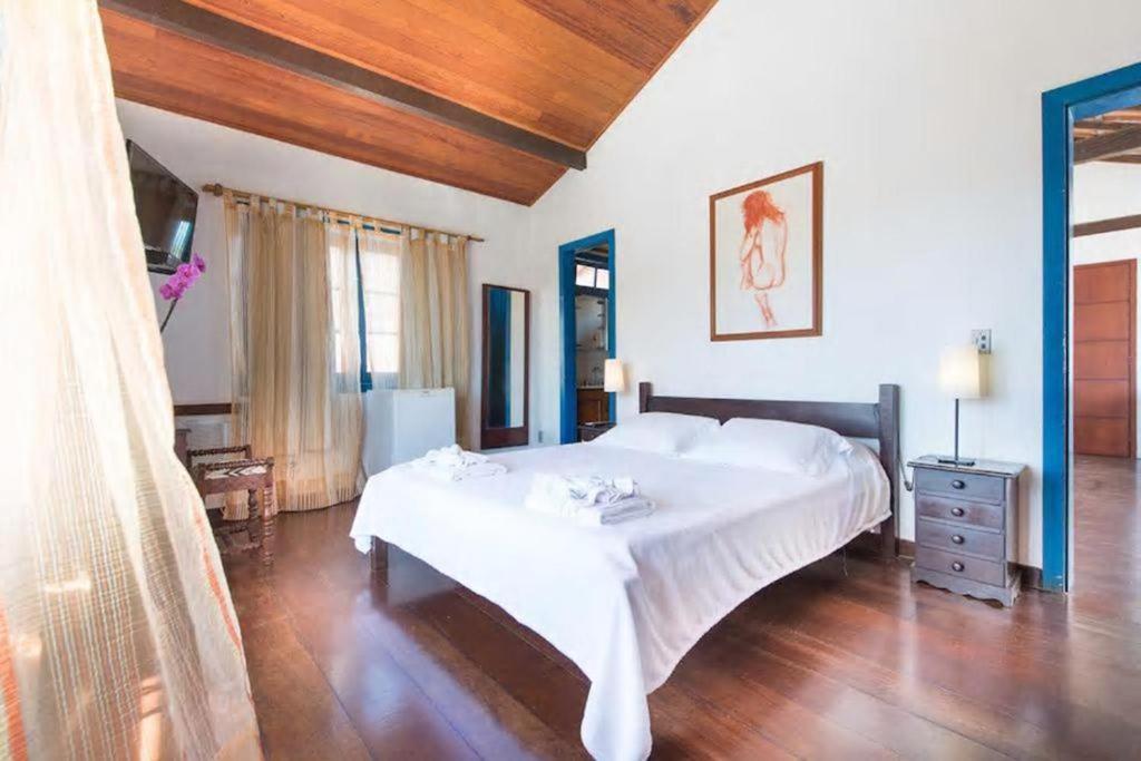 布希奥斯Casa do canto的卧室设有一张白色大床和木地板