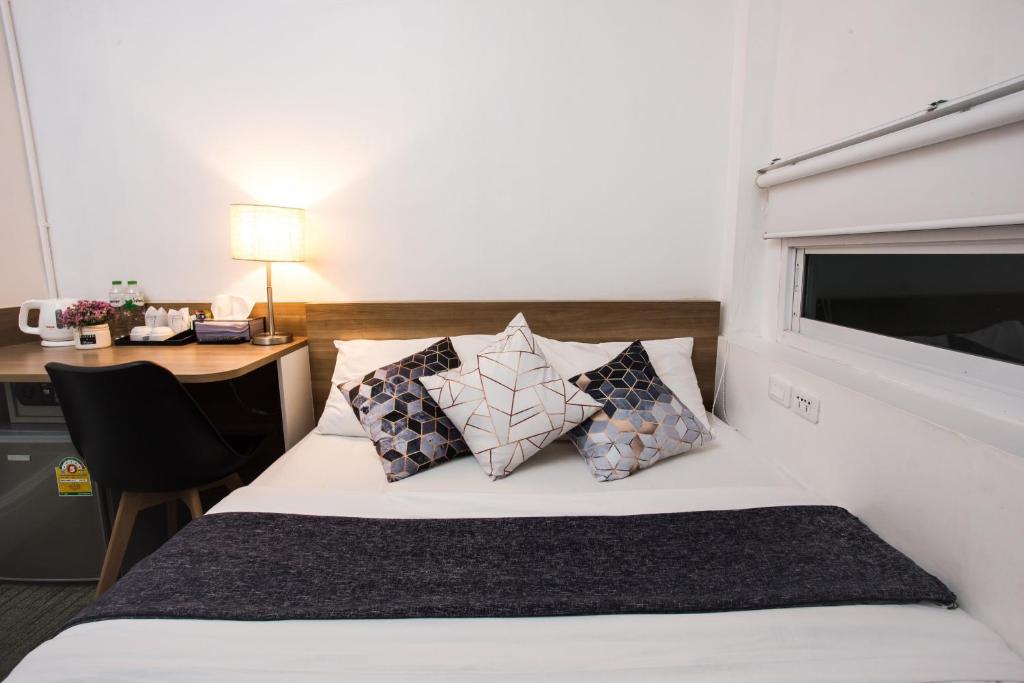 曼谷Qilombo Hostel Silom - HQ的酒店客房设有一张带书桌的床和窗户。