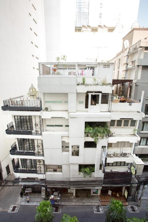 曼谷Qilombo Hostel Silom - HQ的一座高大的白色建筑,上面有植物
