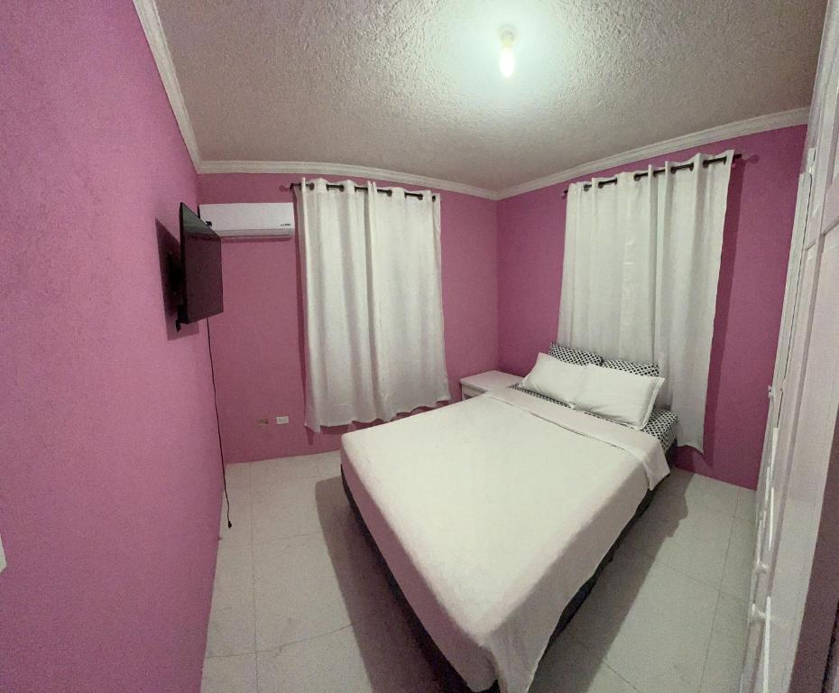 基督教堂市Home away from home的一间小卧室,配有白色的床和粉红色的墙壁