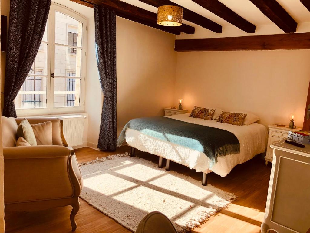 布尔日L’AMANTINE Chambres d’hôtes et gîte的一间卧室配有一张床、一张沙发和一个窗口