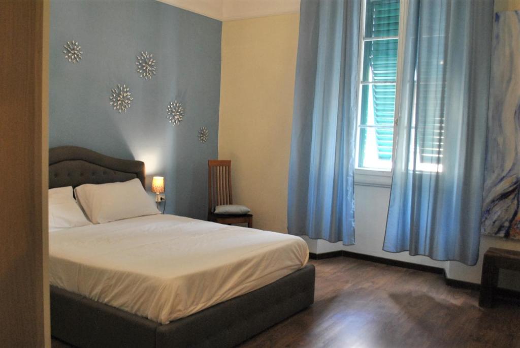普拉托Appartamento Guido的一间卧室配有一张带蓝色窗帘的床和一扇窗户
