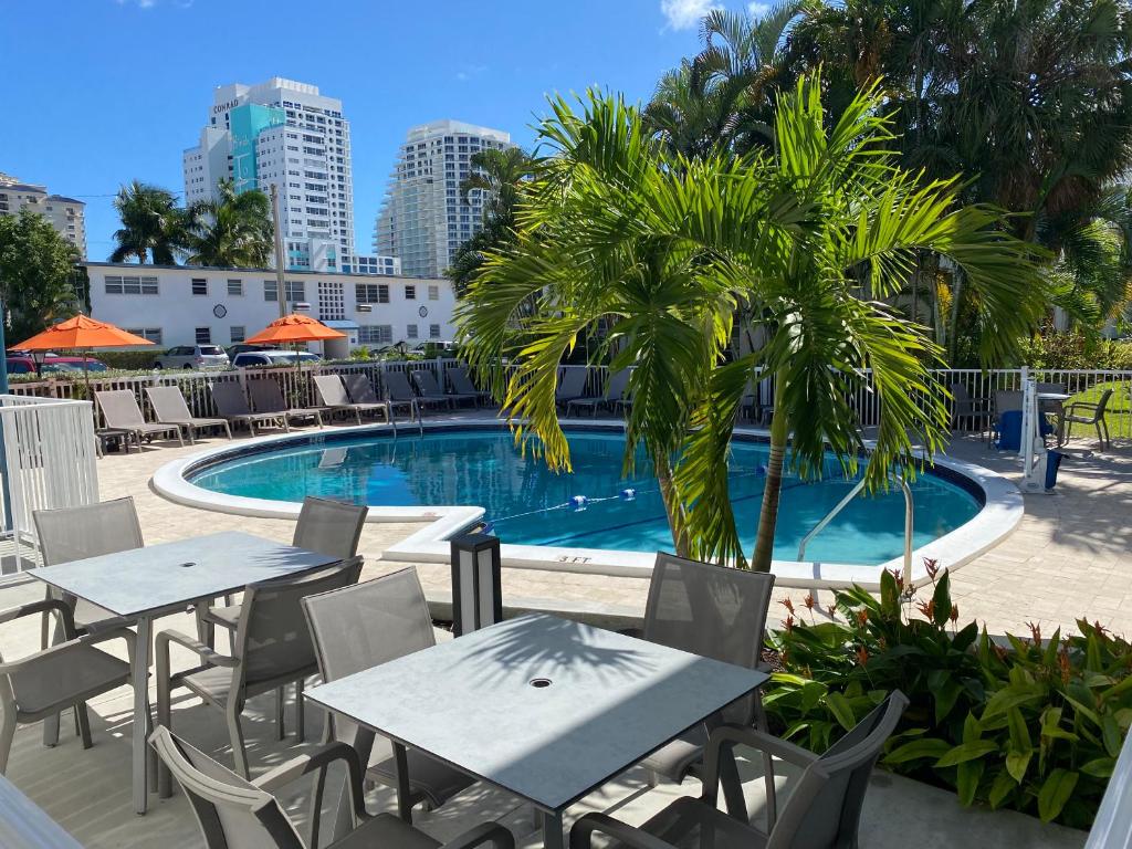 劳德代尔堡Rolo Beach Hotel的一个带桌椅的游泳池,以及棕榈树