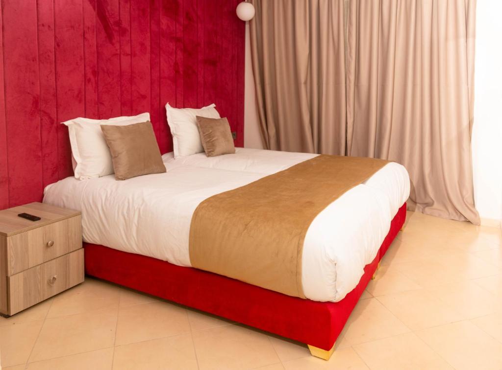 马拉喀什Residence La Perle de l'Atlas Marrakech的一间卧室配有一张大床和红色床头板