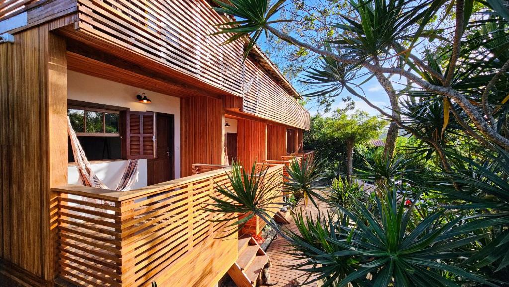 普腊亚罗萨Vila no Rosa Hospedaria的一座木房子,设有棕榈树阳台