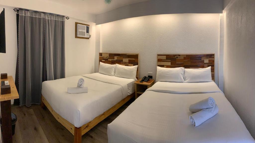 长滩岛El Puerto Boracay Shore的配有白色床单的酒店客房内的两张床