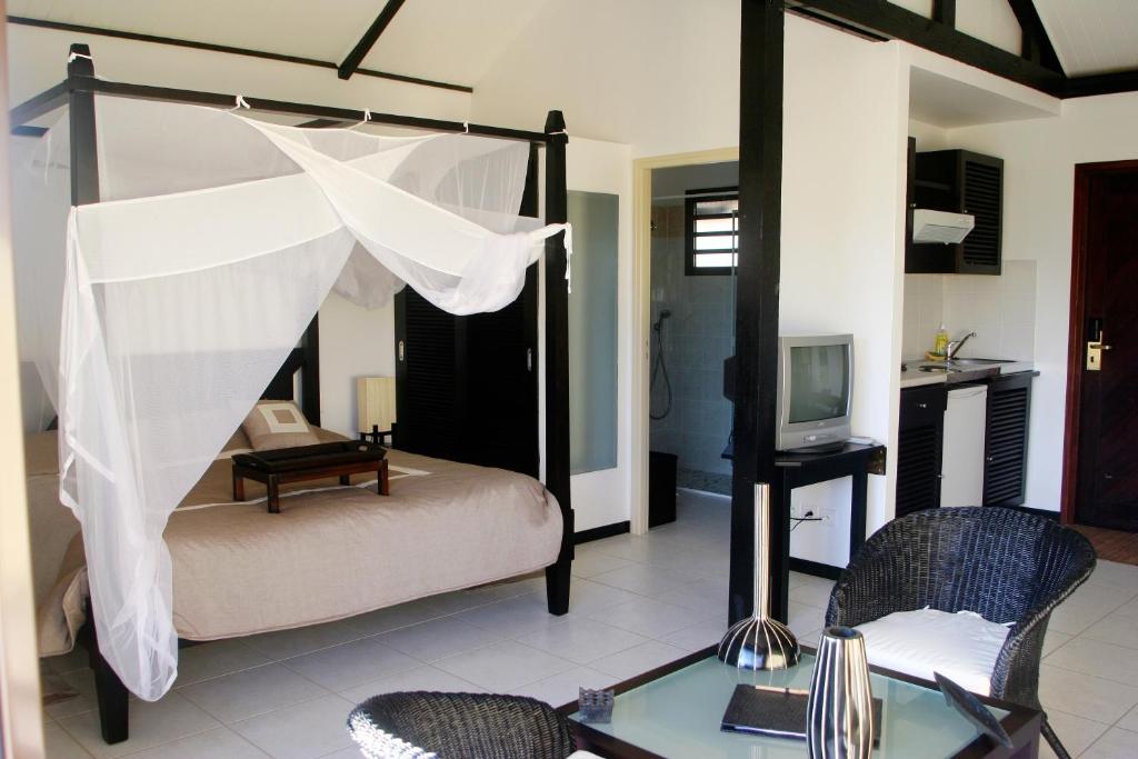PaïtaRivland Resort的一间卧室配有一张带桌椅的天蓬床