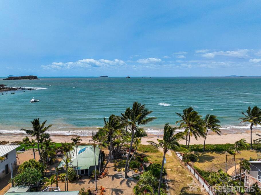 泽尔西Beachfront Holiday Cottage的享有棕榈树海滩和大海的景色