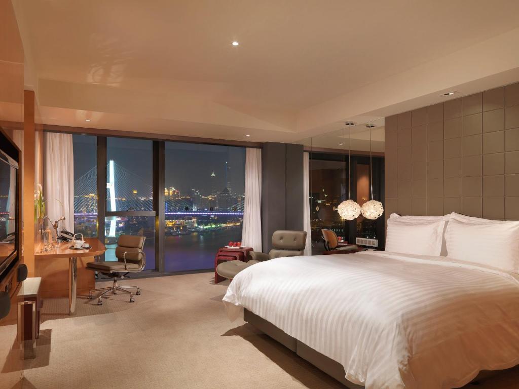 上海上海世博洲际酒店的一间卧室配有一张大床和一张桌子及椅子