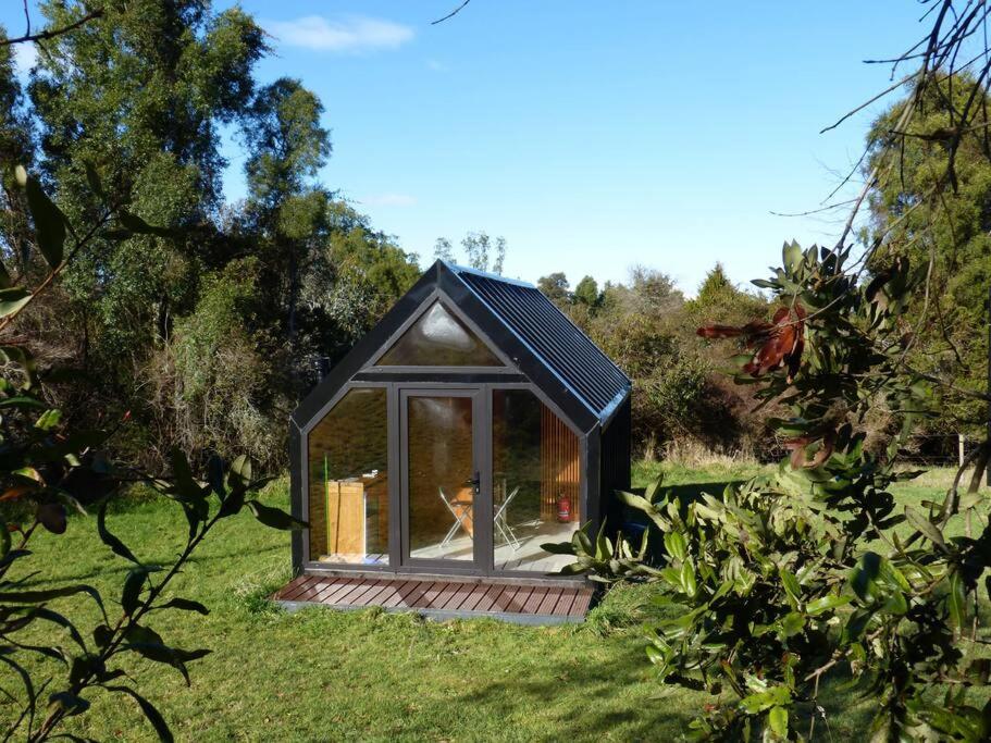 奥克泰港Tiny House Camino a Cascadas, Lago Llanquihue的草上有一扇窗户的小房子