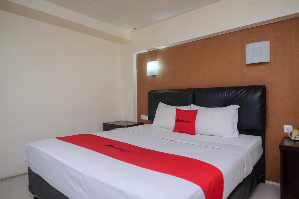 马卡萨RedDoorz Plus At Grand Populer Hotel的一间卧室配有一张大床和两个红色枕头