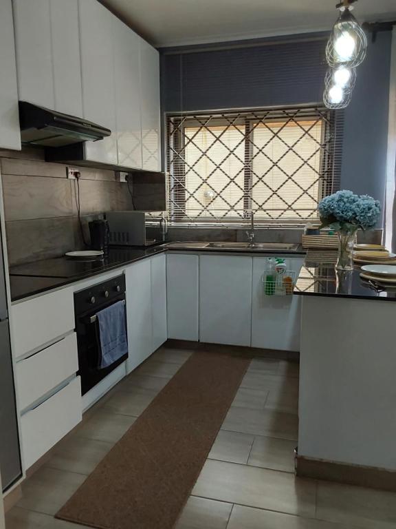 利隆圭Rena Apartment的一间设有白色橱柜和窗户的大厨房