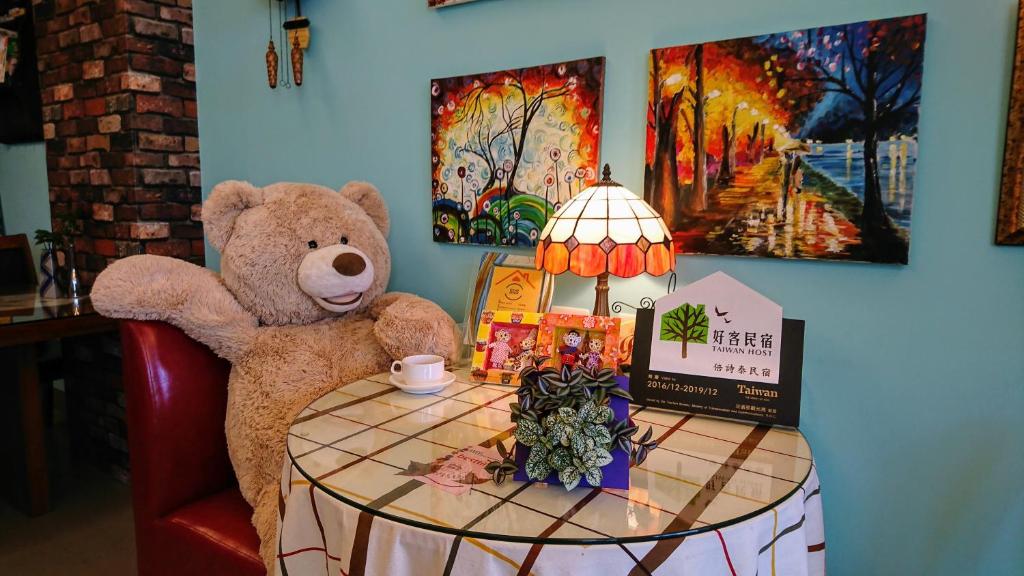 集集镇倍诗泰民宿 的坐在桌子旁边的椅子上的泰迪熊