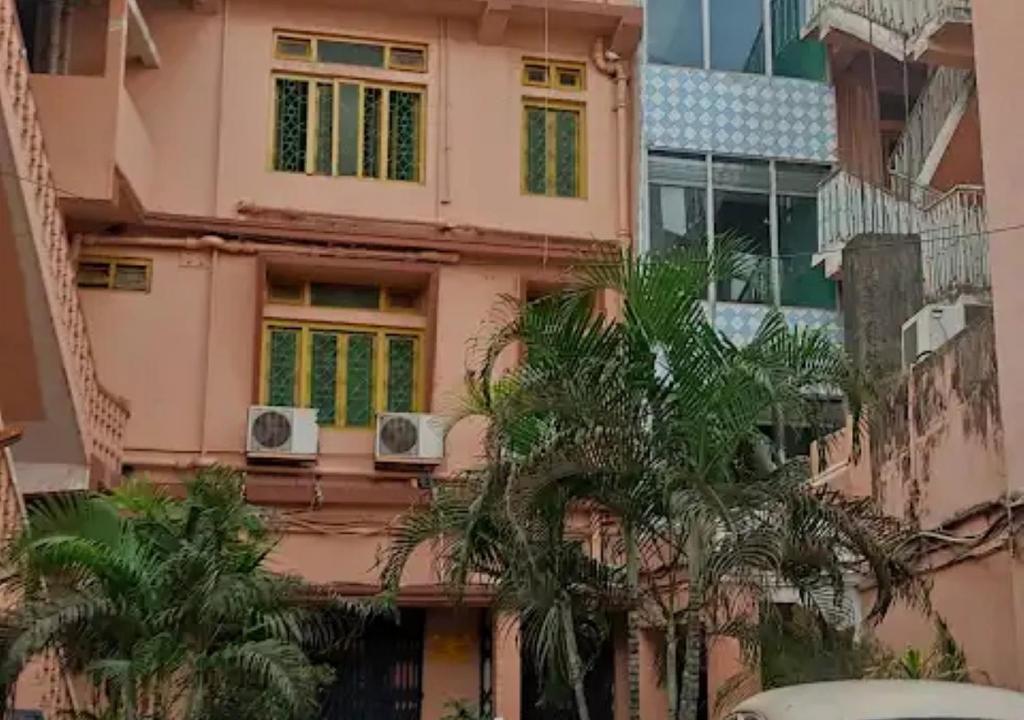 RourkelaHotel Chanderlok Odisha的粉红色的建筑,有两个窗户,棕榈树