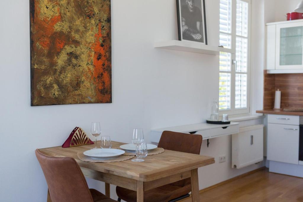 格拉茨Pleasant City Apartment的厨房配有木桌、椅子和绘画作品