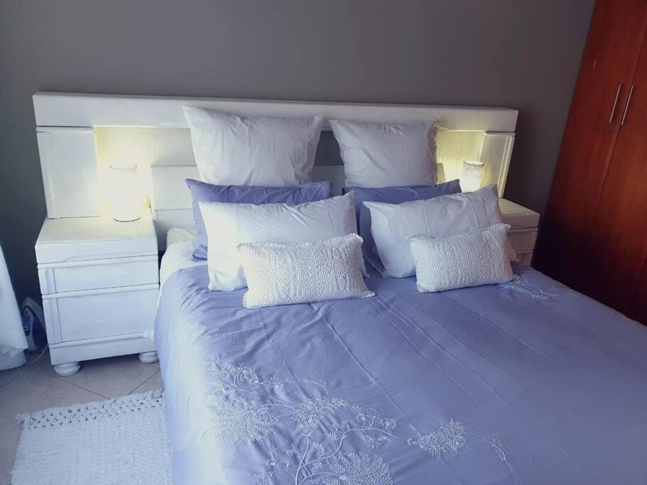 逊邱伦36 Petrel Road的一张带蓝色棉被和白色枕头的床