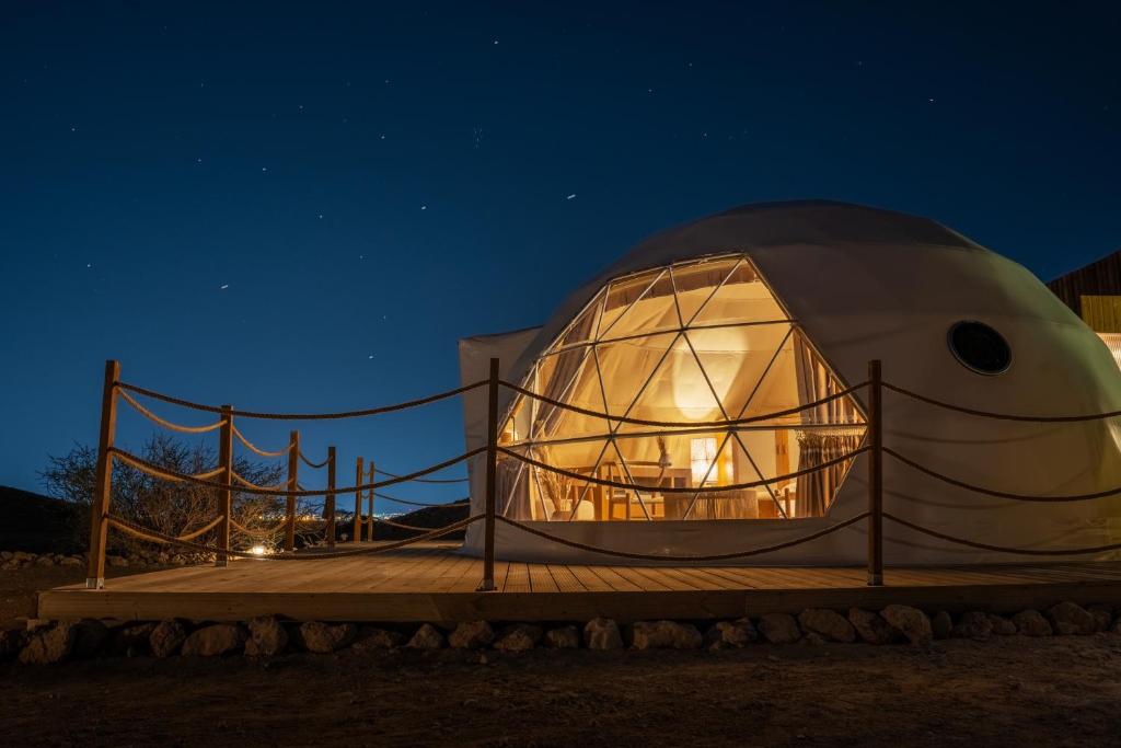 艾恩Pura Eco Retreat, Jebel Hafit Desert Park的 ⁇ 顶房子,晚上有玻璃门