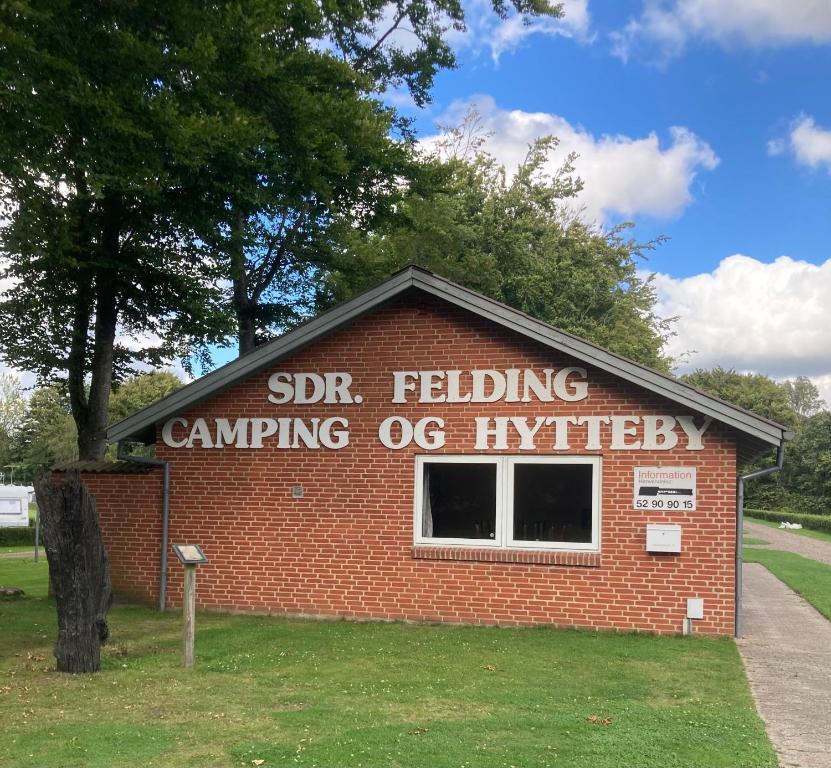 Sønder FeldingSdr. Felding camping & hytteby的砖楼边的标志