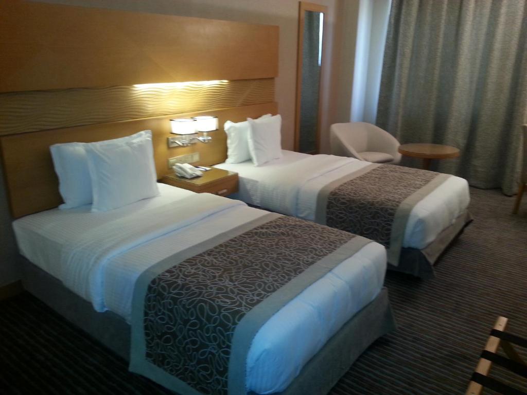 埃尔比勒Hotel Hilen De Ville的酒店客房,配有两张床和椅子