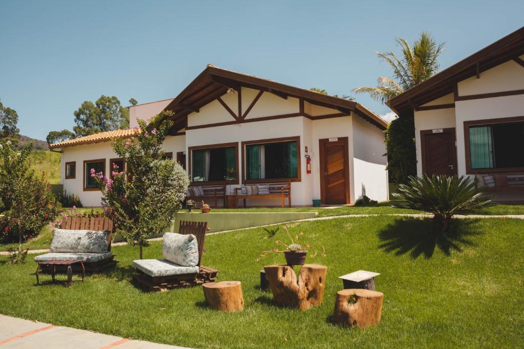 卡皮托利乌Pousada Vale do Chapéu的房屋,设有庭院,配有两把椅子和木柴