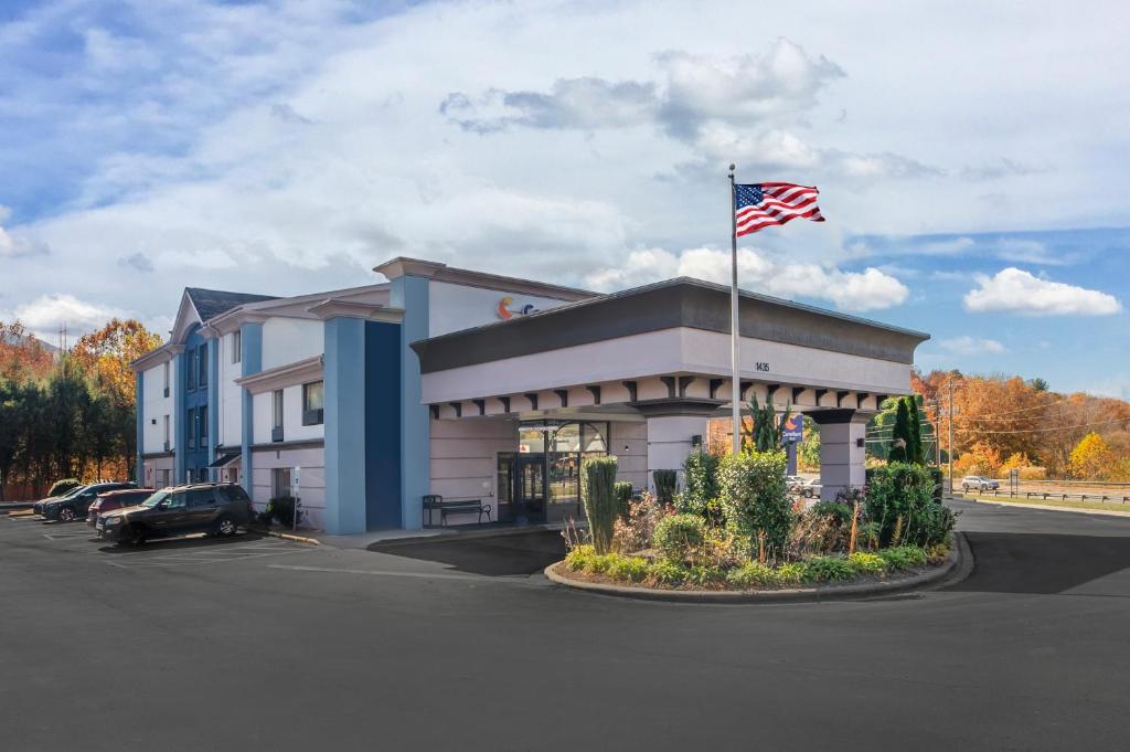 阿什维尔Comfort Inn Asheville East-Blue Ridge Pkwy Access的停车场内悬挂美国国旗的建筑物