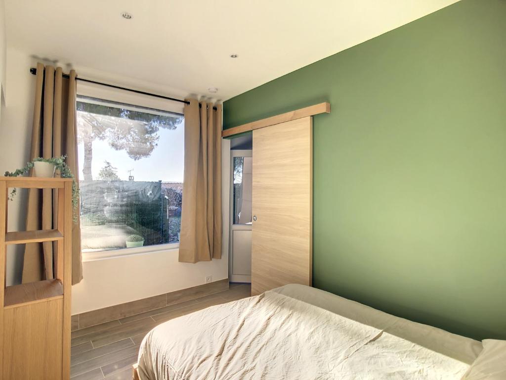 维特罗勒Appartement aux salins du lion的一间卧室设有绿色的墙壁和一张带窗户的床