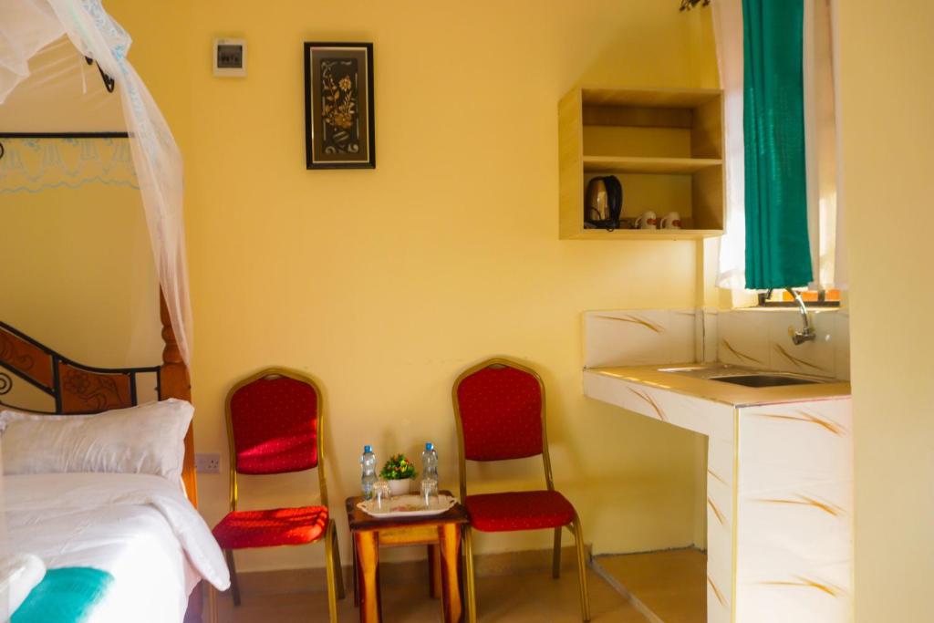 Kitengela Four Wheels Gardens Hotel & Accommodation的一间卧室配有两把椅子、一张床和一张书桌