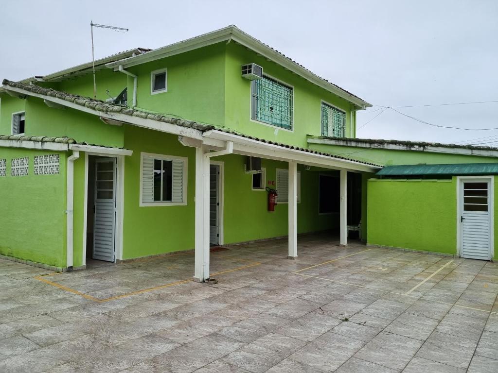 卡拉瓜塔图巴Kitnets em Caraguatatuba的一座绿色房子,前面设有停车位