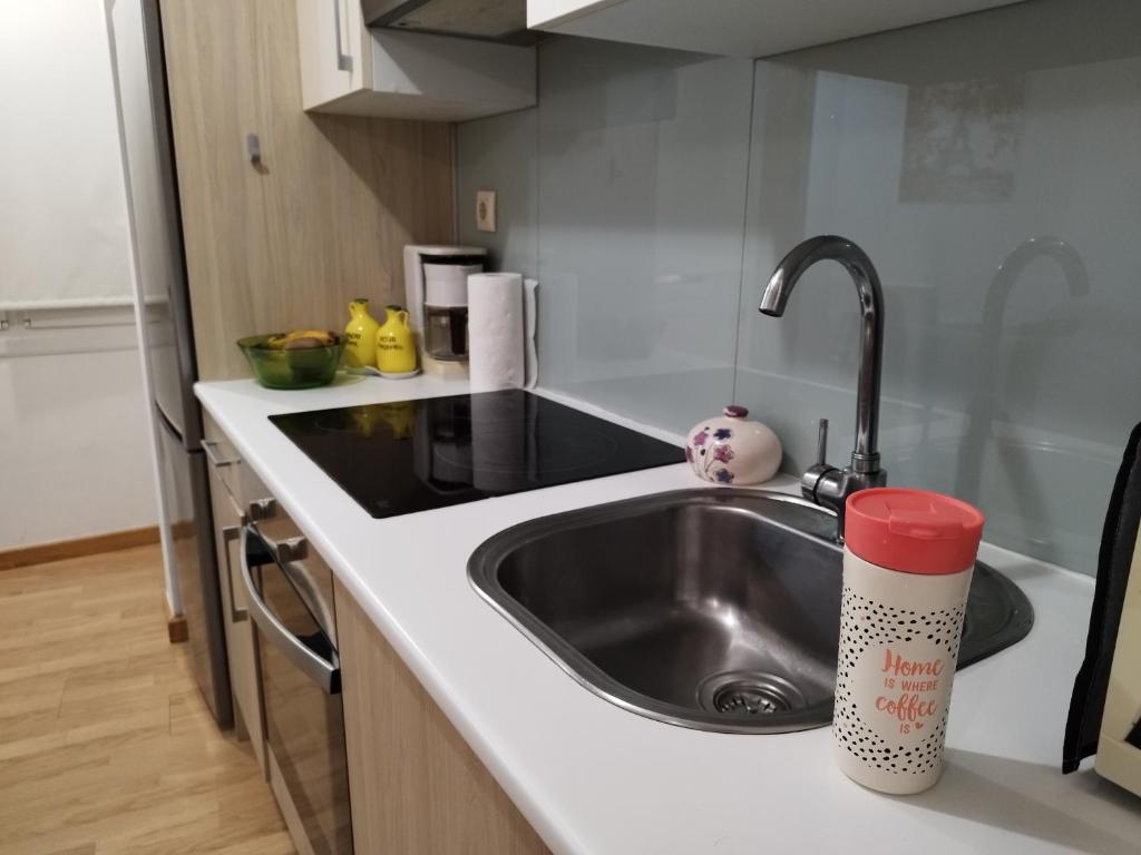 巴约讷Precioso Apartamento en Baiona Zona Centro的厨房水槽和柜台上的红色杯子
