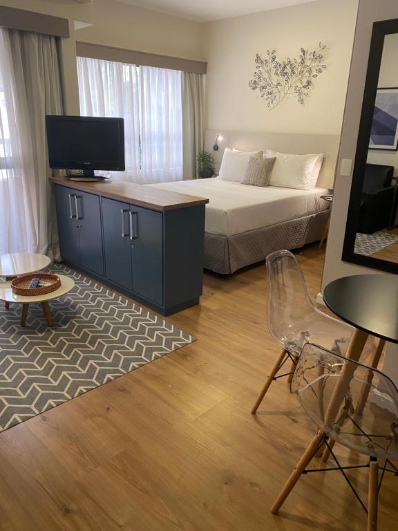 圣保罗Flat Jardins, entre Av Paulista e Parque do Ibiraquera的一间卧室配有一张床、一台电视和一把椅子