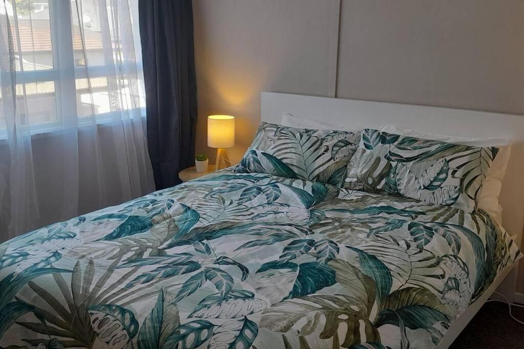 纳尔逊City Central的一间卧室配有一张带绿色和白色棉被的床