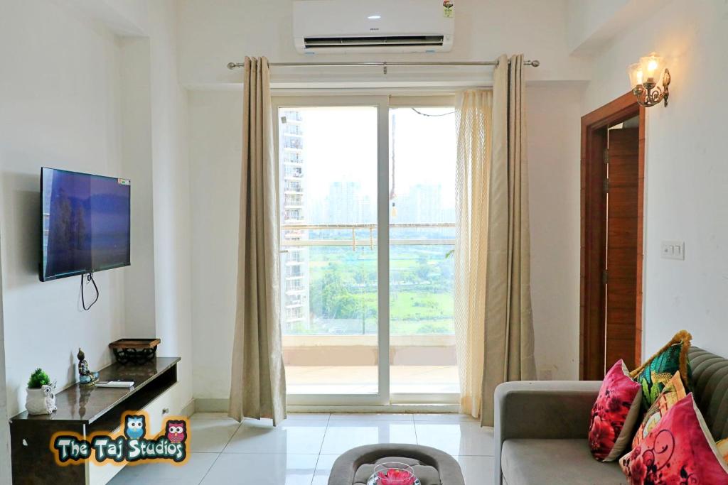 诺伊达The Taj Studios-2Bhk Flat in North Eye Stay with Friend & Family的带沙发和大窗户的客厅