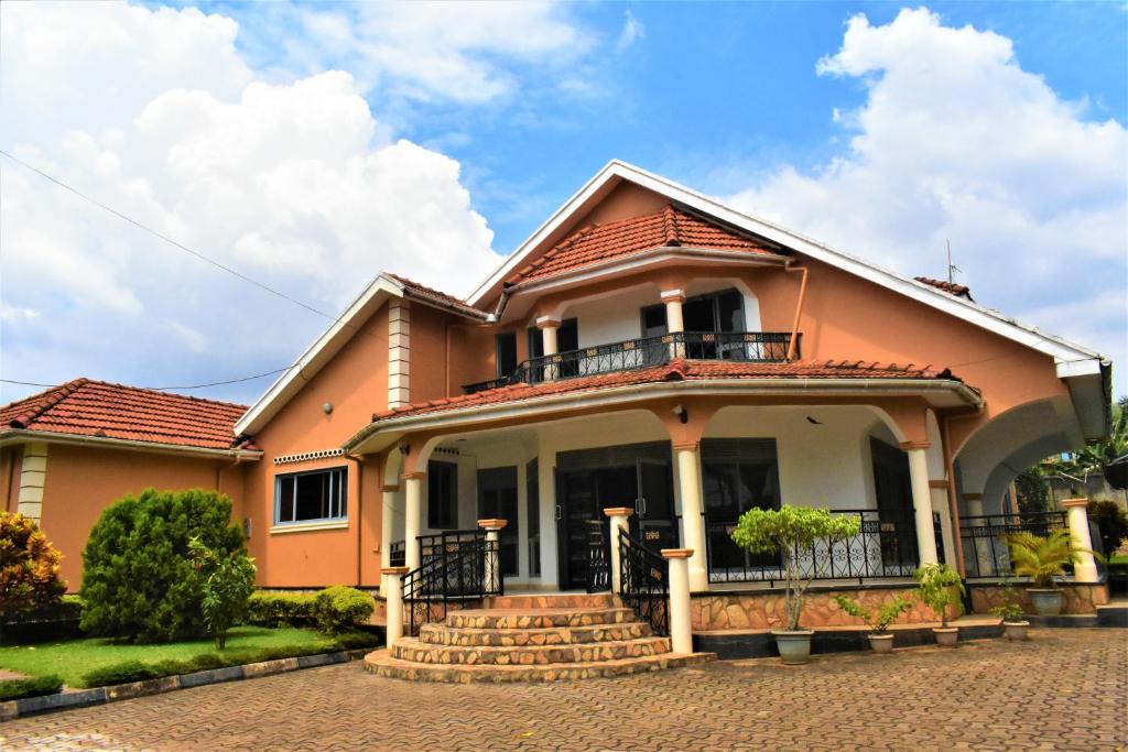 坎帕拉Beautiful home opposite Speke Resort Munyonyo near Lake Victoria的一座大型橙色房屋,设有阳台和楼梯