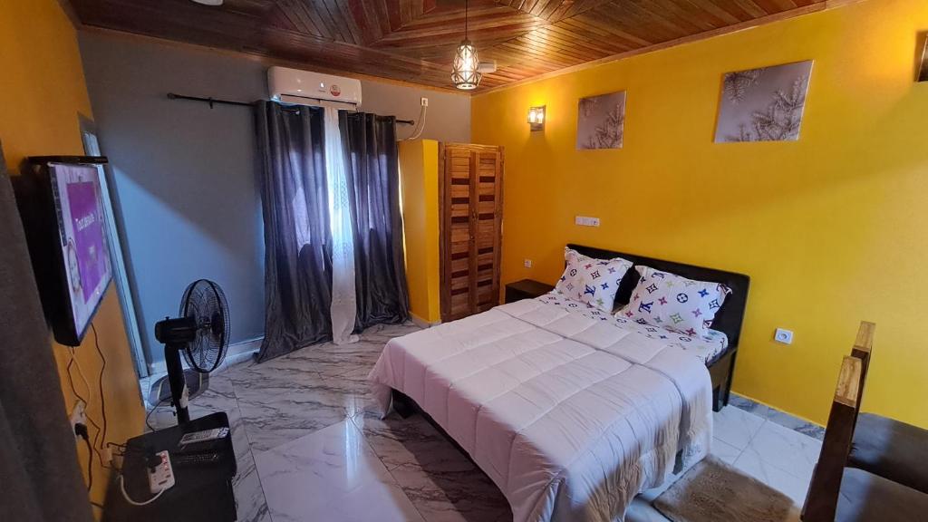 克里比Résidence Chimene Paradis "Chambres"的一间卧室设有一张床和黄色的墙壁