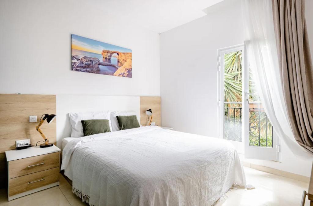 斯利马Hammock Vibes Town House的白色的卧室设有一张大床和一个窗户