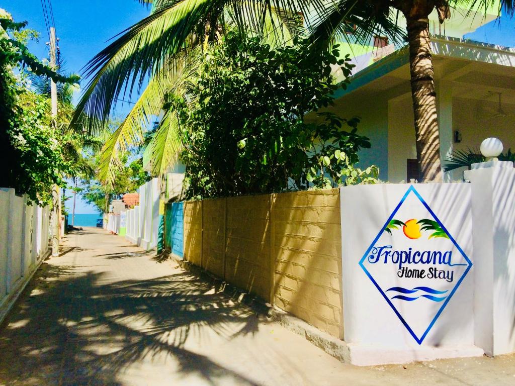 阿鲁甘湾Tropicana Home Stay的房屋前墙上的标志