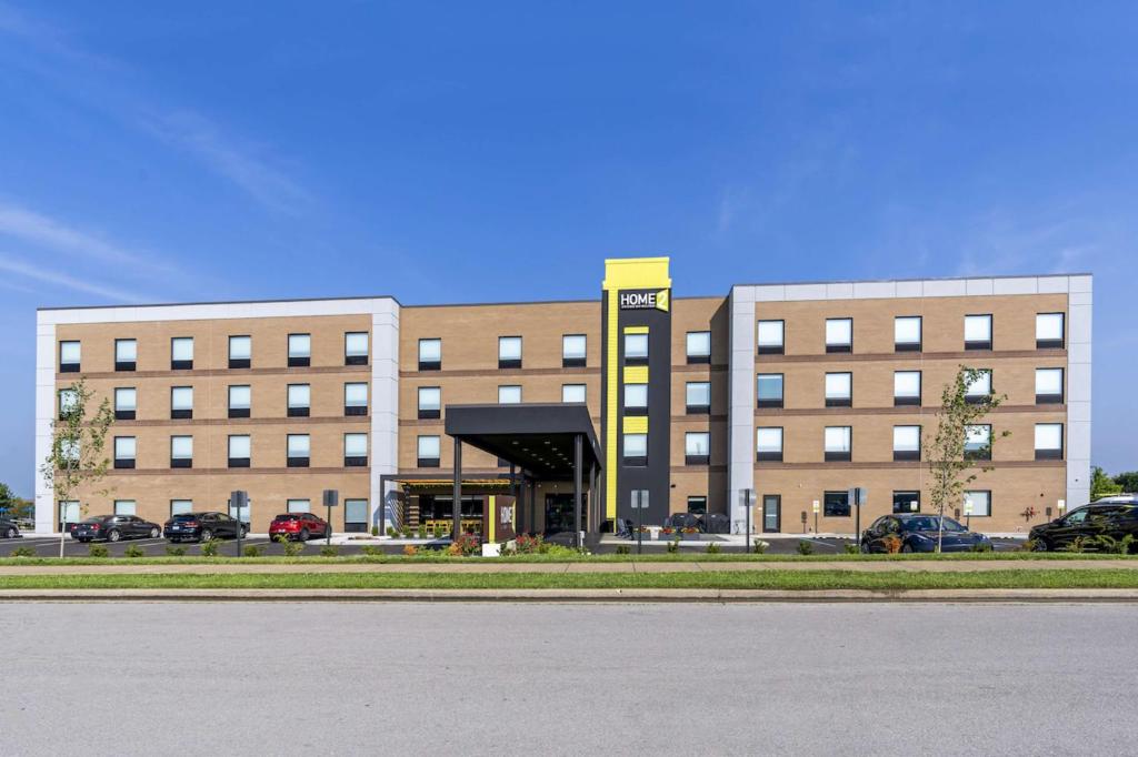 列克星敦Home2 Suites Lexington Keeneland Airport, Ky的一座大型建筑,前面有汽车停放