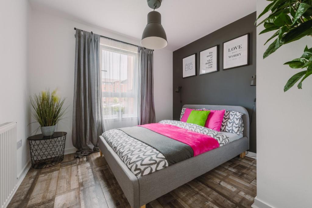格拉斯哥RelaxingSleep Apartments的一间卧室配有带粉色和绿色枕头的床