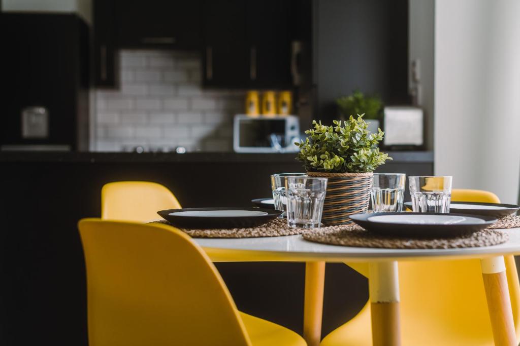 格拉斯哥SleepWell Apartments的一张桌子,上面有盘子,玻璃杯,还有黄色的椅子