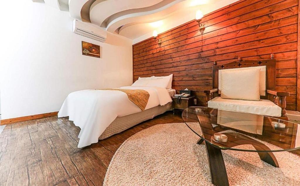 天安市Cheonan Business Hotel的一间卧室配有一张床和一张玻璃桌