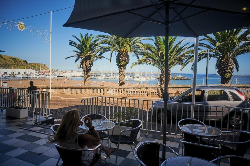 普拉亚达维多利亚Hotel Varandas do Atlântico by RIDAN Hotels的坐在桌子上欣赏海滩景色的女人