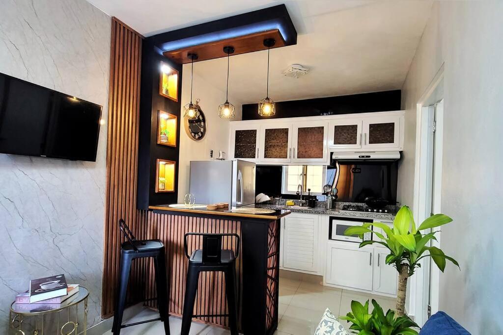 圣地亚哥洛斯卡巴Apartamento acogedor Ashmi的一间厨房,配有白色橱柜和一个带凳子的酒吧