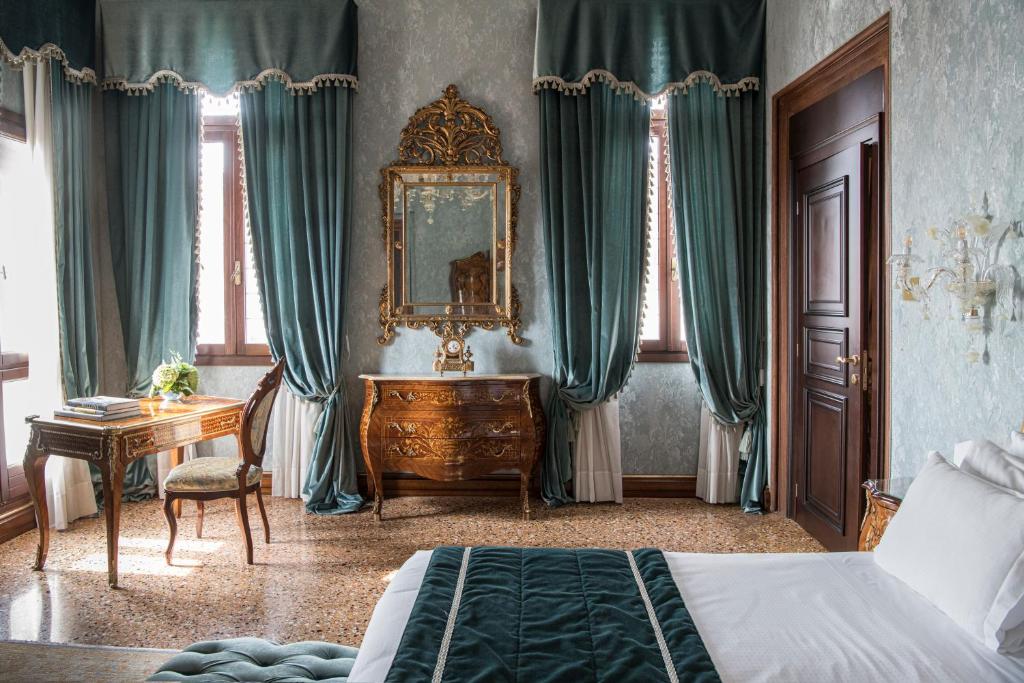 威尼斯纳尼莫切尼戈宫酒店的一间卧室配有一张床、一张书桌和一面镜子