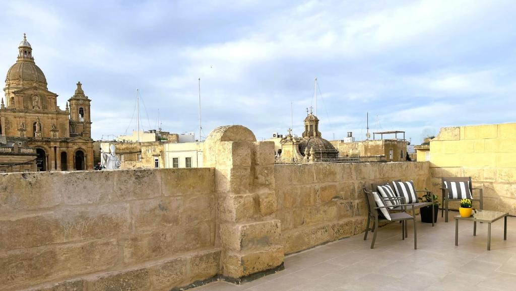 SiġġiewiThe Siggiewi Suites的阳台配有两把椅子和一张墙上的桌子