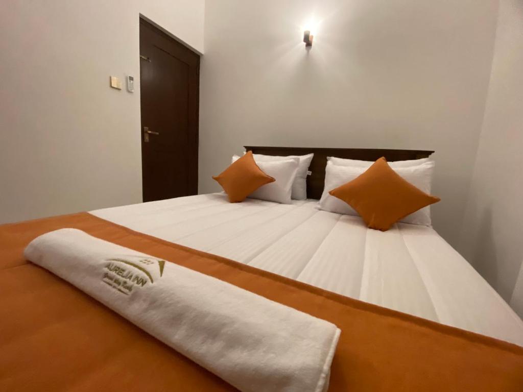 康提Aurelia inn的一间卧室配有一张带橙色和白色枕头的大床