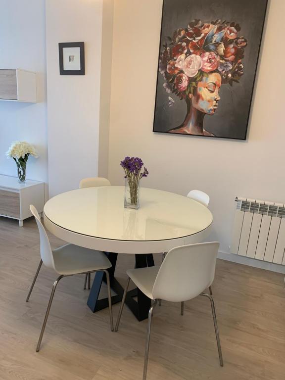 巴约讷Acogedor apartamento en Baiona的一间配备有白色桌椅的用餐室