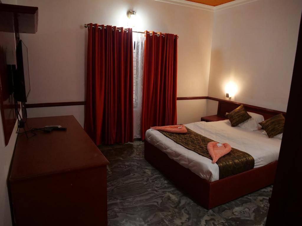 瓦尔卡拉Hosteller's的酒店客房,配有床和红色窗帘